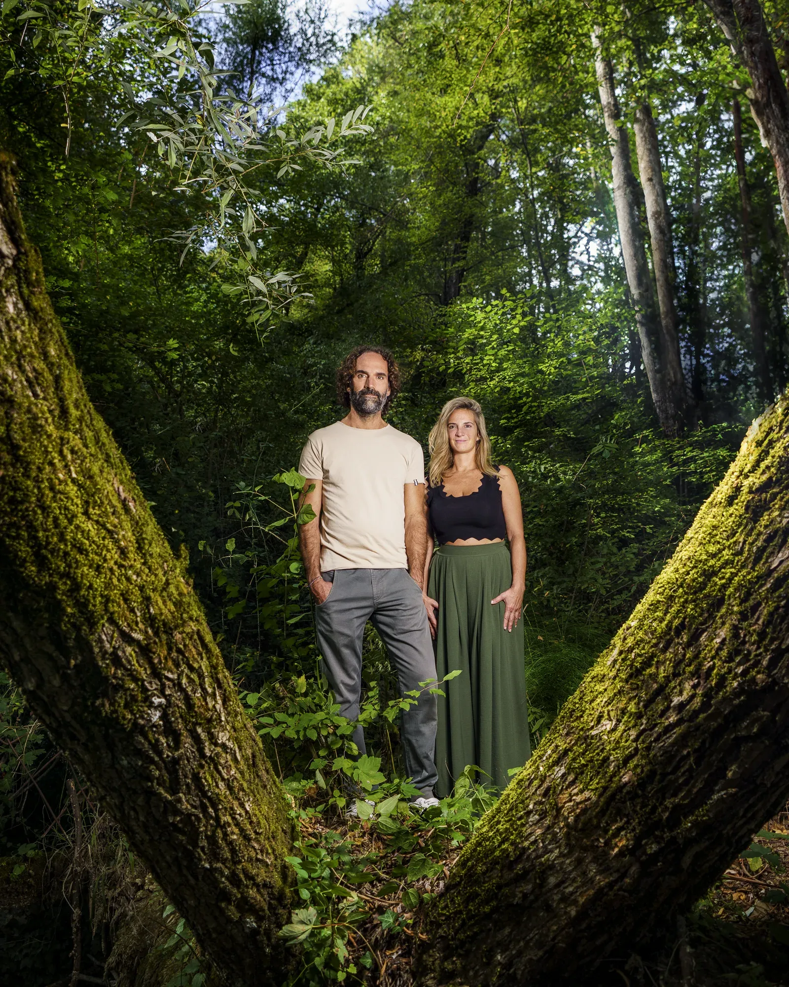 Stefano Spaccapanico Proietti e Francesca Delicati in piedi nel bosco, tra due tronchi