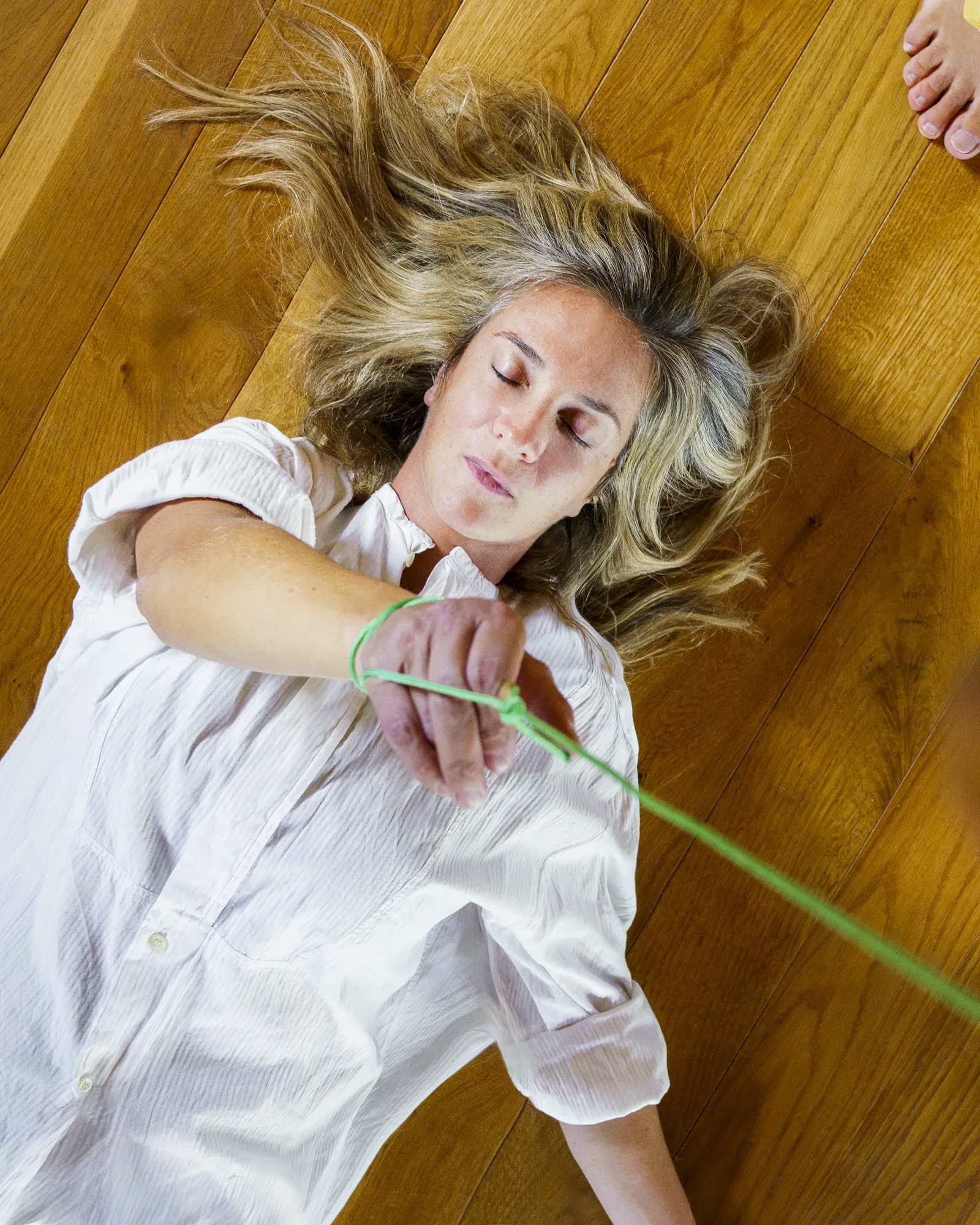 Francesca Delicati distesa sul pavimento, un filo verde tra le dita