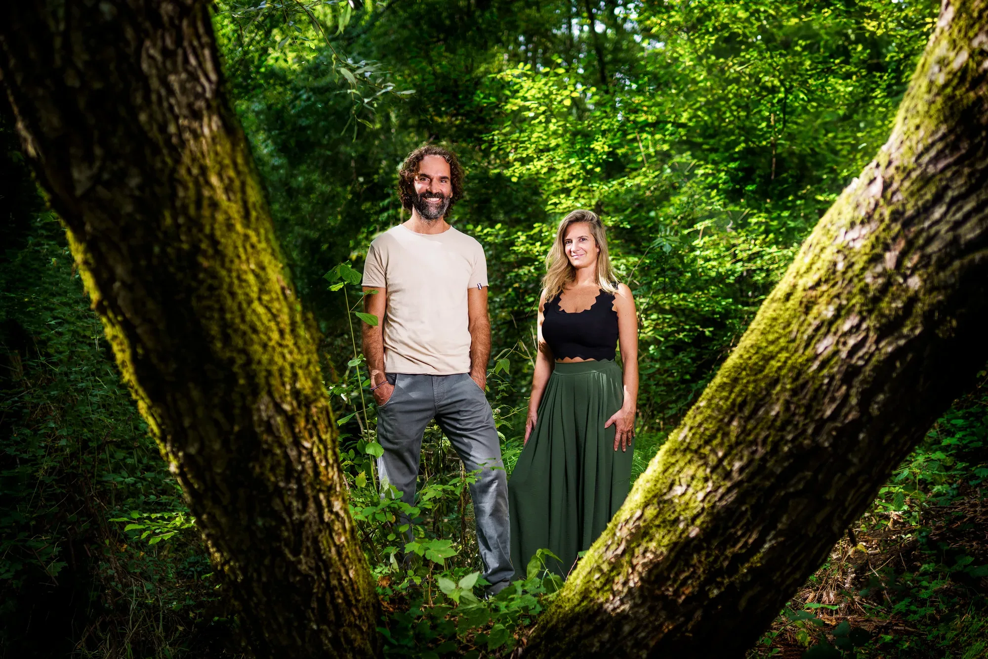 Stefano Spaccapanico Proietti e Francesca Delicati in piedi nel bosco, tra due tronchi